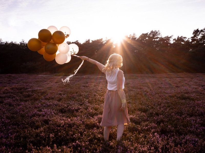 Julia Ritter steht auf einem Feld mit Luftballons in der Hand. Sie ist glücklich und lebt ihren Ikigai. Ikigai, japanisches Lebenskonzeot, Ikigai finden