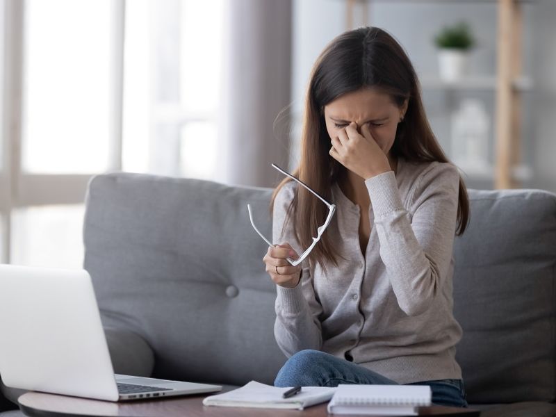 Business-Tipps, Frauen im Business, müde Frau reibt sich die Augen, mit Brille in der Hand sitzend vor dem Laptop, Tipps für die Selbstständigkeit